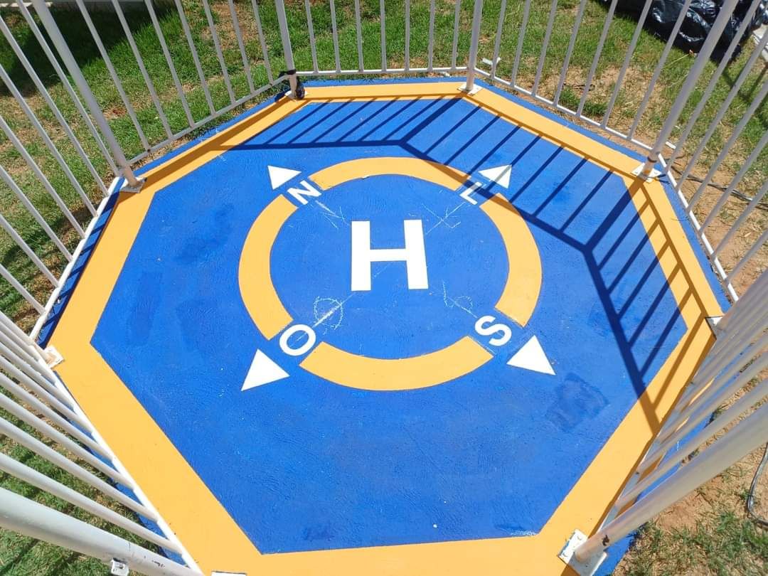 Heliponto pintado em azul e amarelo com a letra H e os pontos cardeais