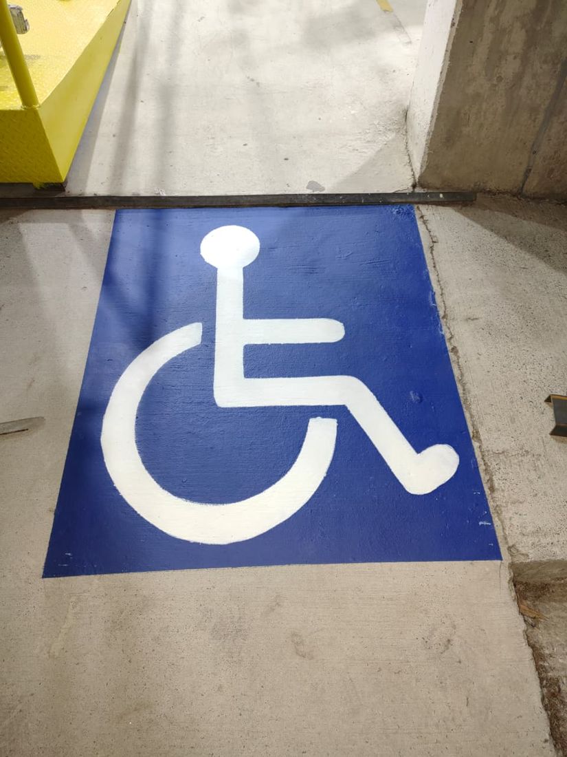 Símbolo de acessibilidade pintado em azul no piso de concreto